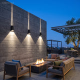 Three outdoor sconces lighting a terrace wall above a fire pit lounge