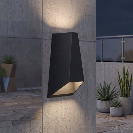 Black wedge outdoor wall sconce lighting a concrete wall above and below