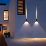 Two outdoor sconces casting cones of light on a pale house facade
