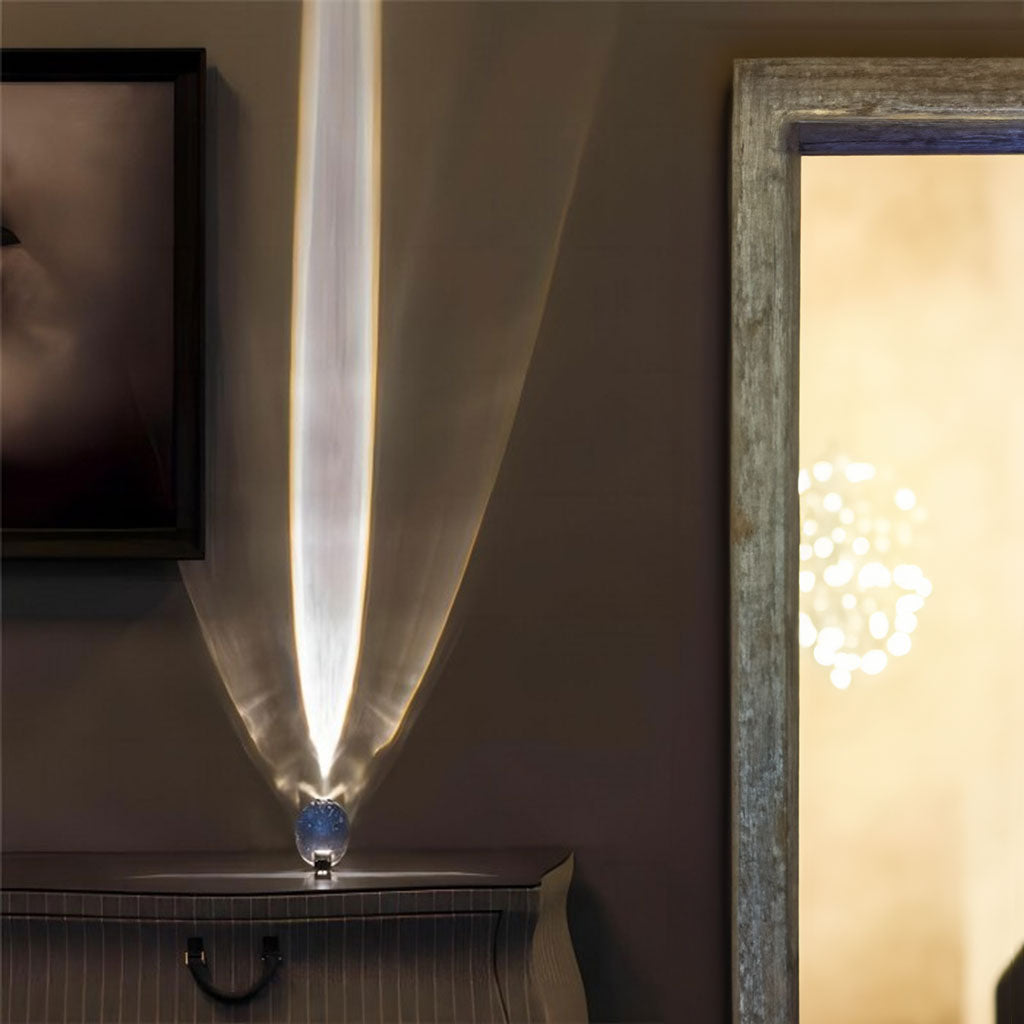 Oval glass table lamp glowing warm on a dark surface