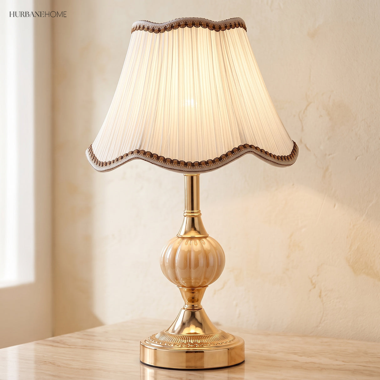 Warm-lit gold glass table lamp beside a green plant and teacup
