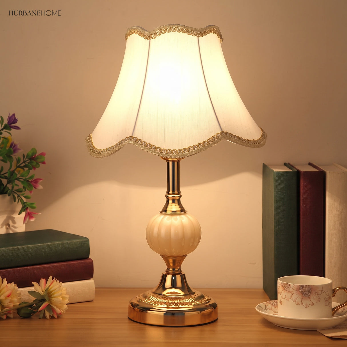 Glass table lamp with white shade next to stacked books