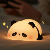 Panda silicone night light glowing warm white as it rests on soft bedding