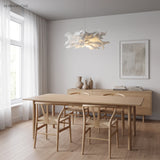 White paper pendant light hanging above a pale oak dining table by a window
