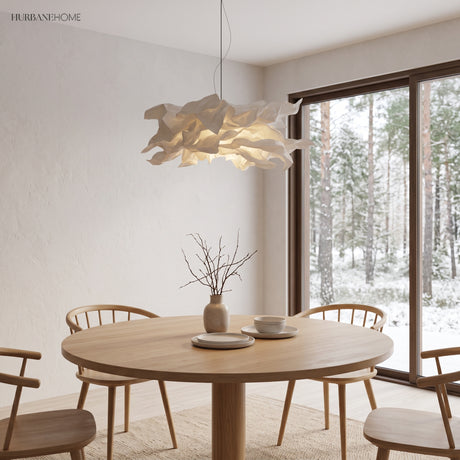 Paper pendant light above a round dining table facing a snowy forest window