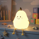 Smiling pear silicone night light glowing softly among wooden toys and stars