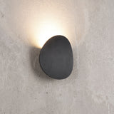 Pebble shaped outdoor LED wall light in matt black on a concrete wall