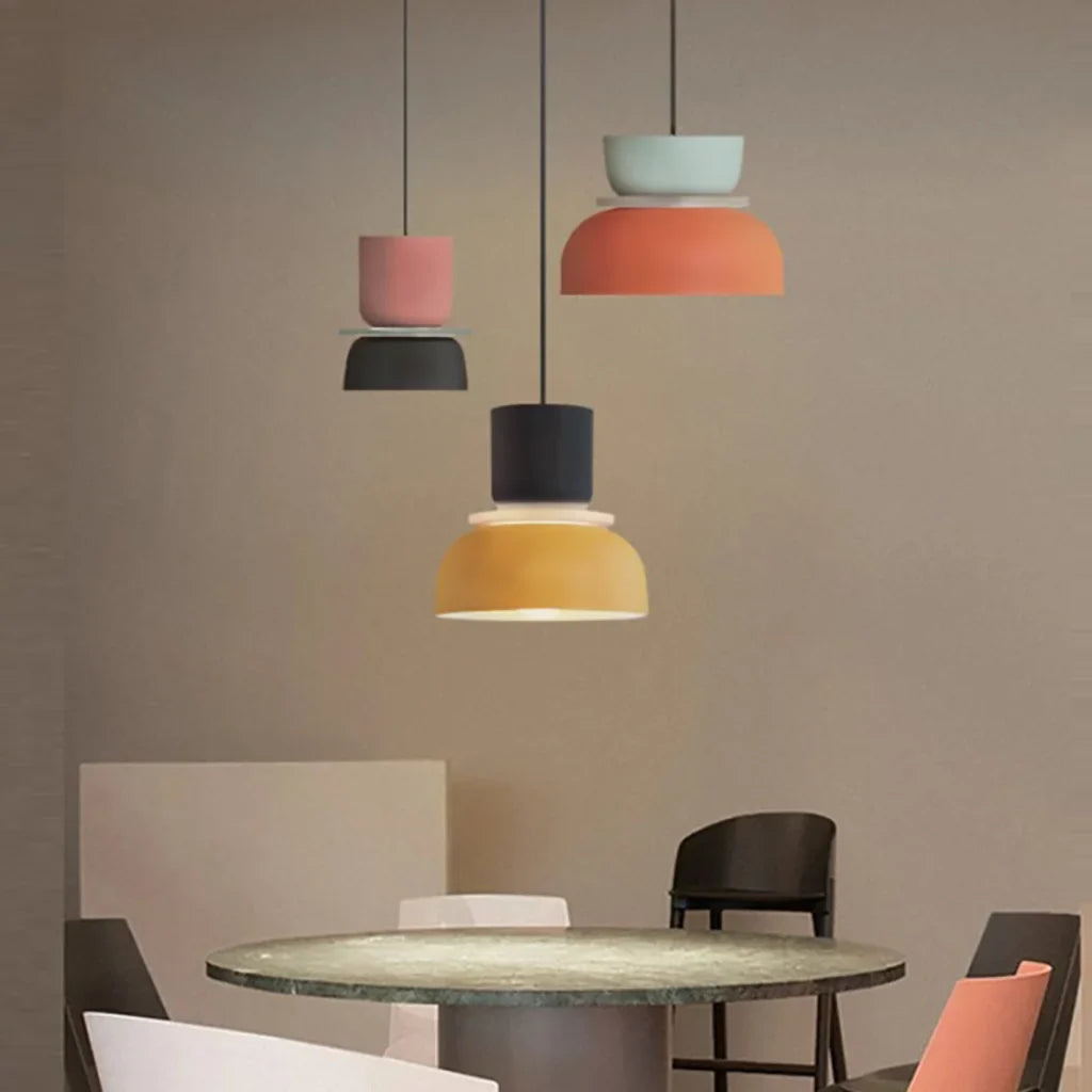 Three colorful pendant lights above a brown dining table