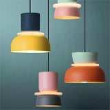 Four colorful pendant lights against a teal wall