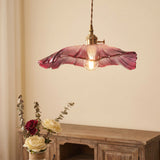 Close view of the ruffled pink glass shade and brass lamp holder above roses