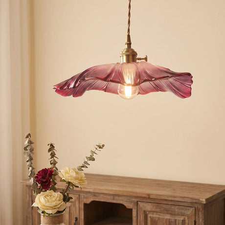 Close view of the ruffled pink glass shade and brass lamp holder above roses