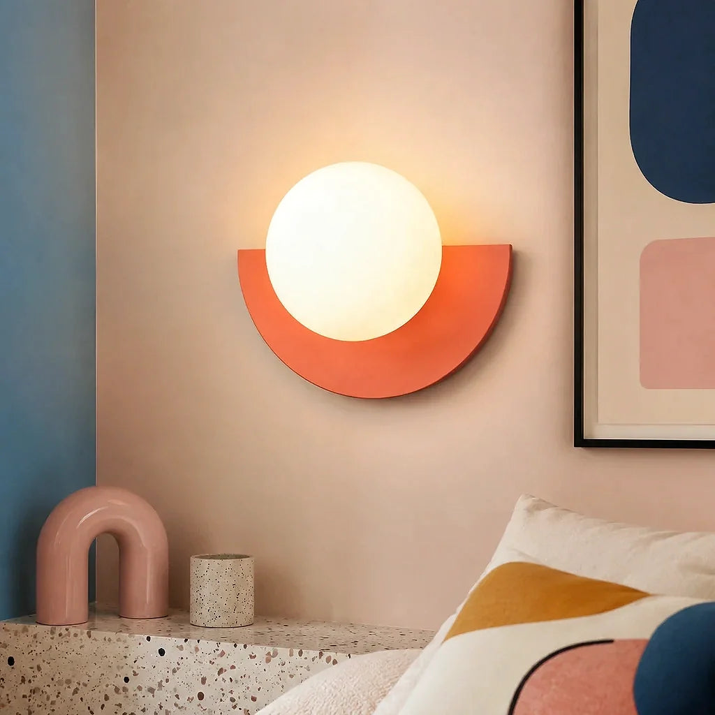 Pink glass globe wall sconce lit with a soft, even glow