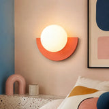 Pink glass globe wall sconce lit with a soft, even glow