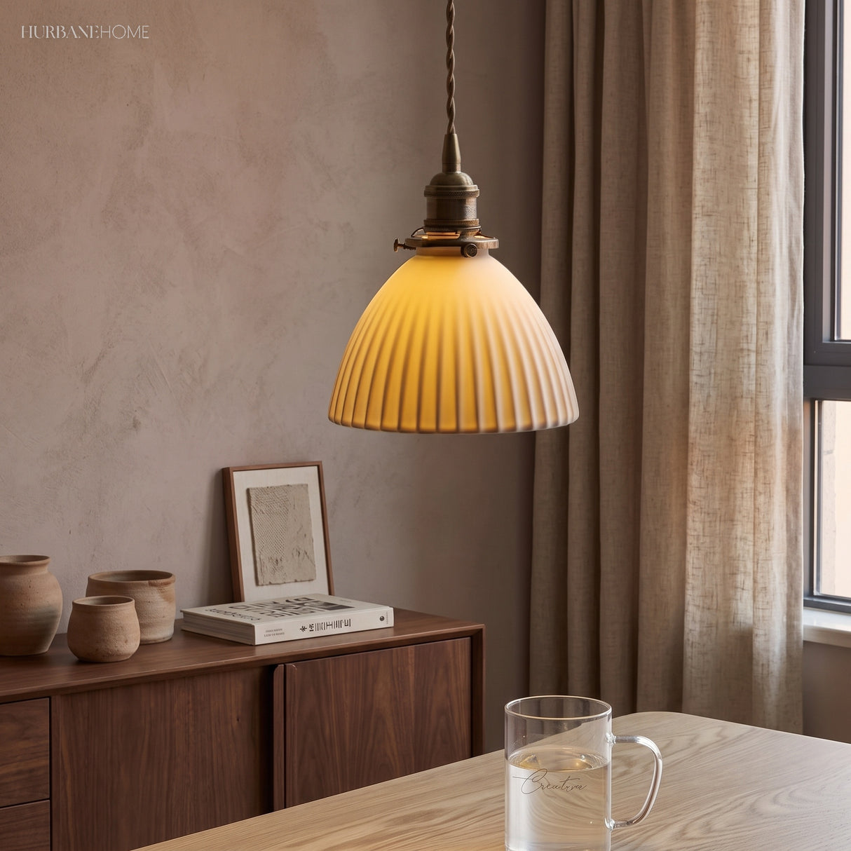 Pleated ceramic pendant glowing warmly above a timber sideboard and jugs
