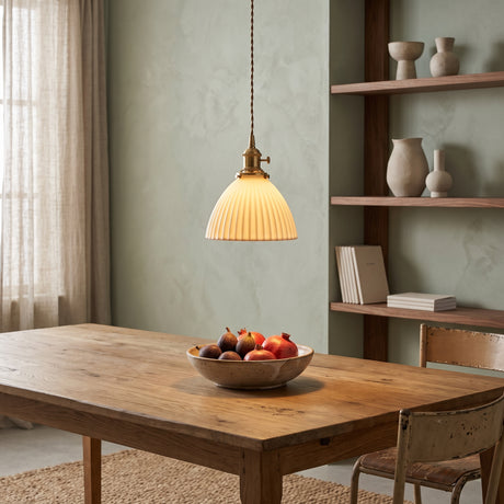 White pleated ceramic pendant with brass fitting above a farmhouse table