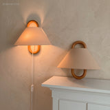 Pleated fabric wall sconce with beechwood mount glowing softly on a wall