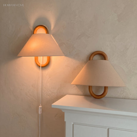 Pleated fabric wall sconce with beechwood mount glowing softly on a wall
