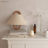 Beechwood-mounted fabric wall sconce lit against a neutral wall