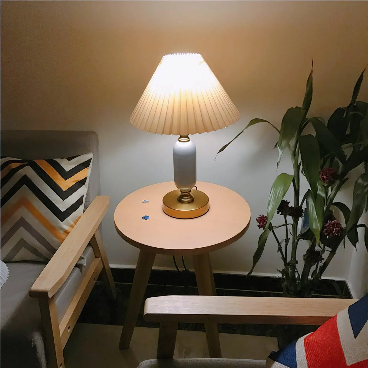 Pleated table lamp lit with warm glow on a white brass base