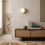 Flush porcelain disc wall light above a cane fronted sideboard