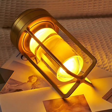 Gold lamp lying on its side on printed pages, still lit through the acrylic
