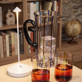 White portable LED table lamp beside a glass jug of iced drink