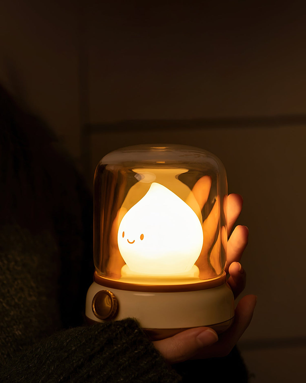 Lit flame night light cupped in a hand in a darkened room
