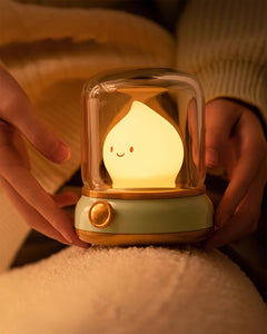 Hand lifting the lit night light from the top of a soft cream blanket