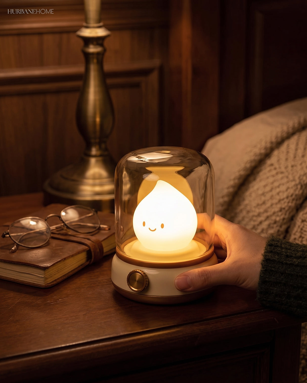 Hand resting on the lit flame night light beside a brass lamp and a globe