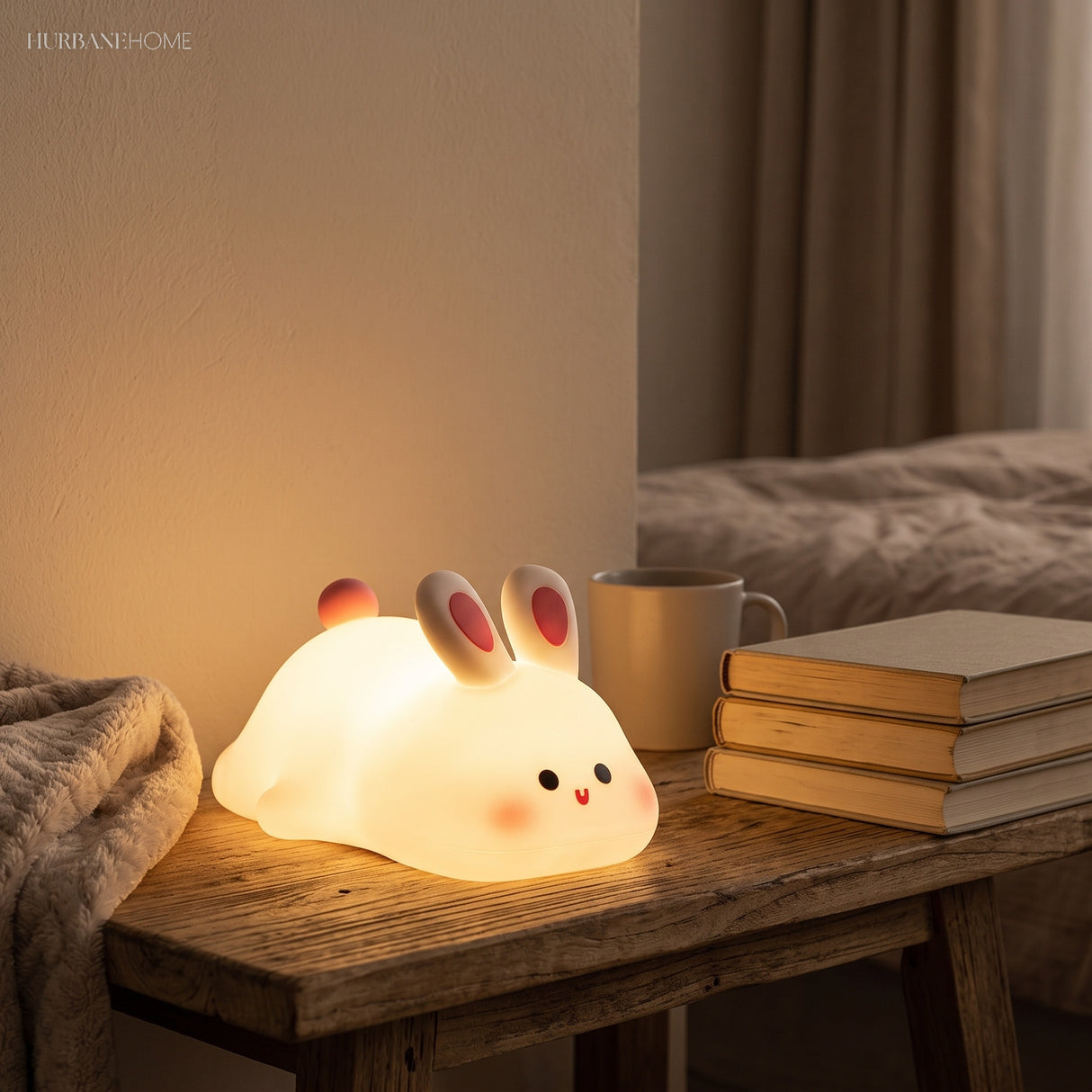 Rabbit silicone night light glowing on a bedside table with books and mug