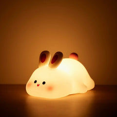 Rabbit silicone night light glowing warm on a table with a soft amber backdrop