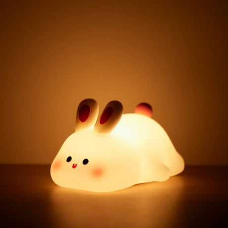 Rabbit silicone night light glowing warm on a table with a soft amber backdrop
