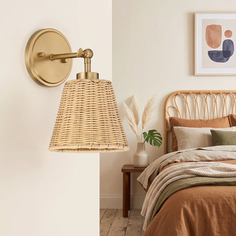 Brass swing arm sconce with woven rattan cone shade above a bed