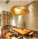 Rattan pendant lit gold above a console with a vase of branches