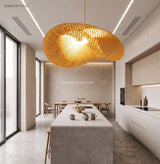 Wide rattan pendant lit above a pale kitchen island and stools