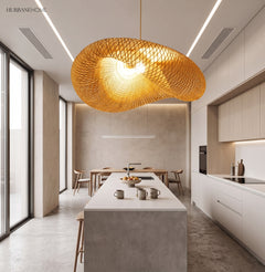 Wide rattan pendant lit above a pale kitchen island and stools