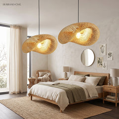 Two bamboo saucer pendants lit above a bed with linen bedding