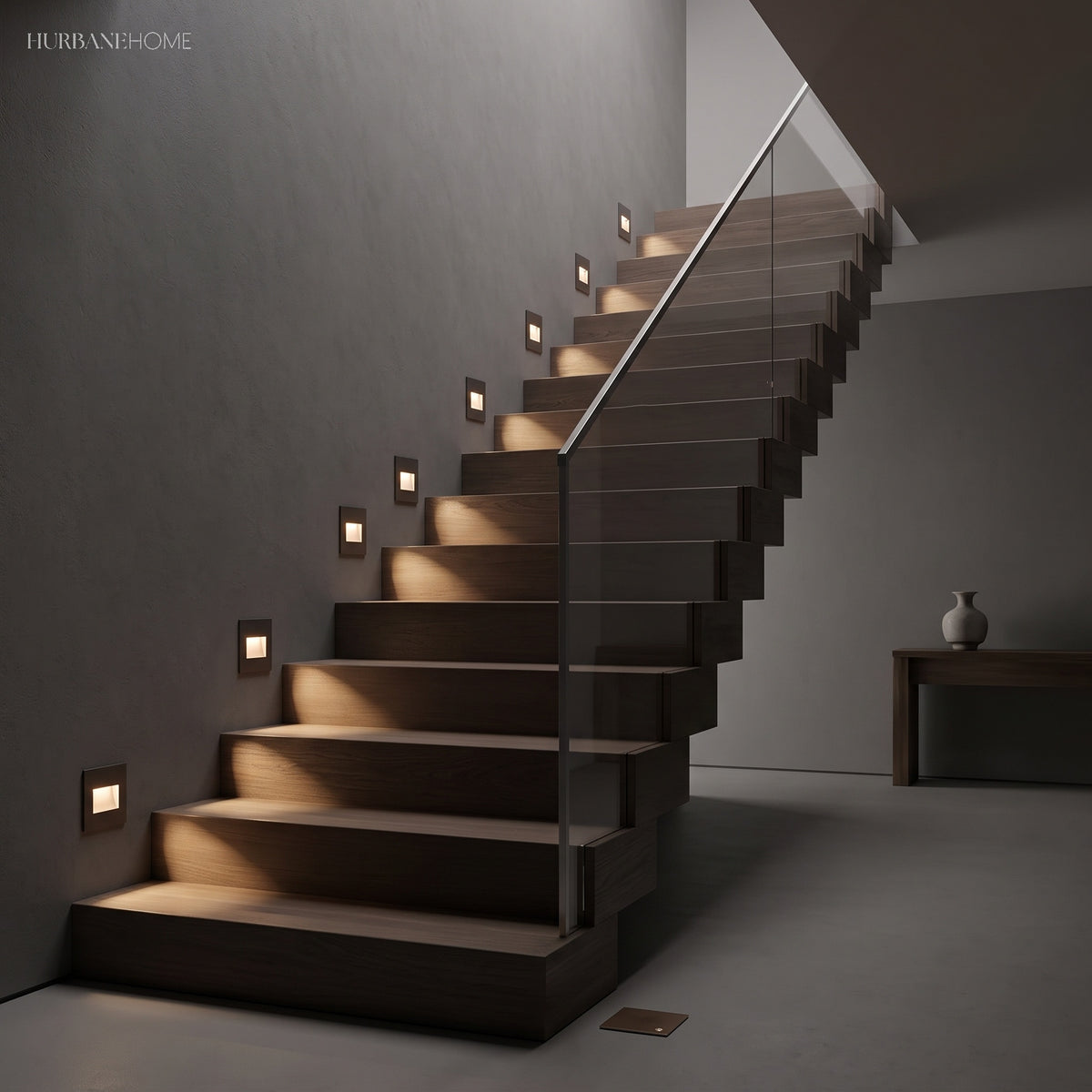 Square step lights running up a dark staircase with a glass balustrade