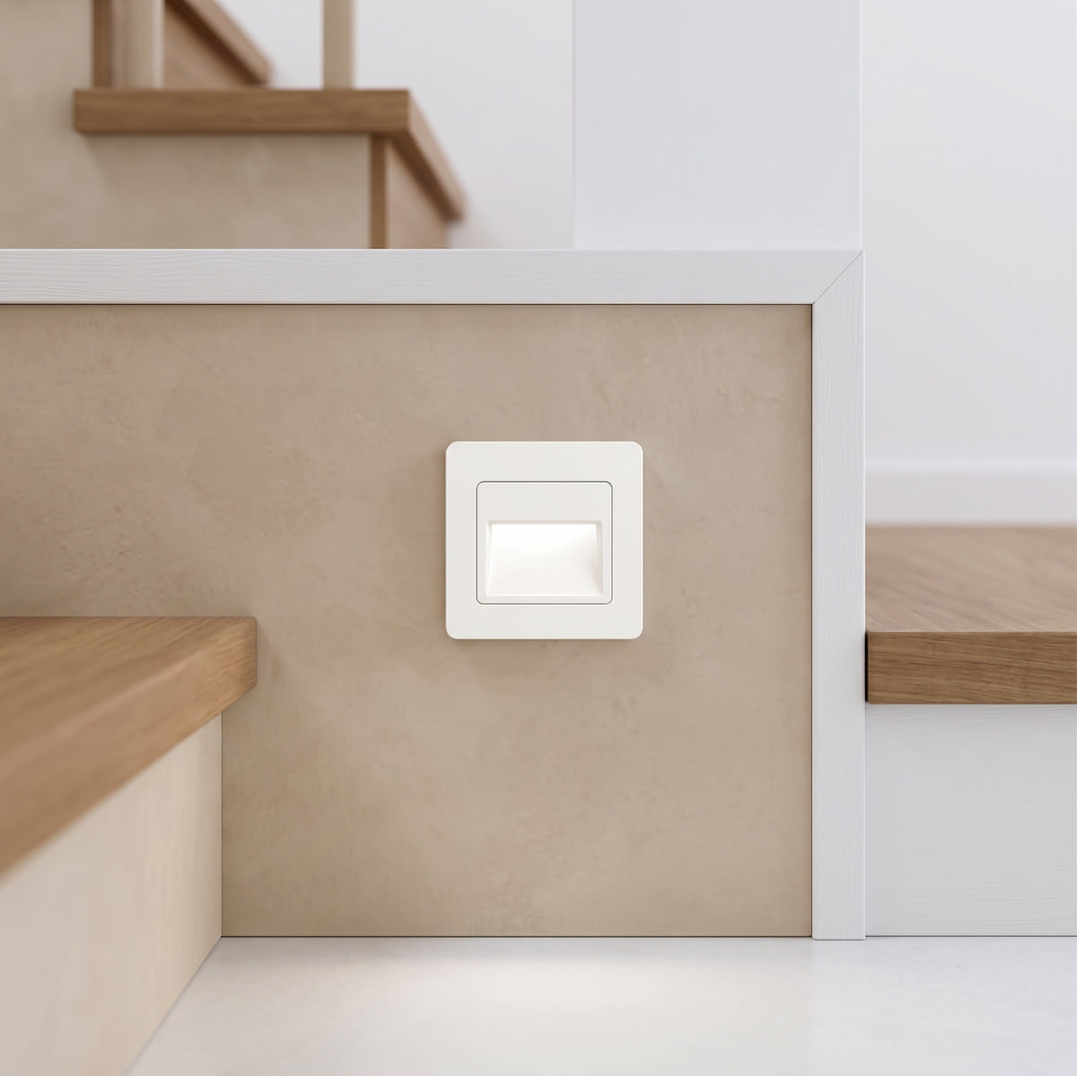 Square white recessed stair light set low into a pale wall beside timber steps