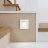 Square white recessed stair light set low into a pale wall beside timber steps