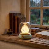 Rechargeable flame night light with a green base and clear dome on a wooden table