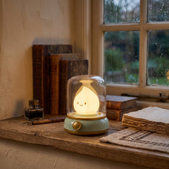 Rechargeable flame night light with a green base and clear dome on a wooden table