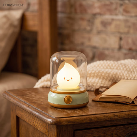 Green based flame night light glowing on a wooden side table beside an open book