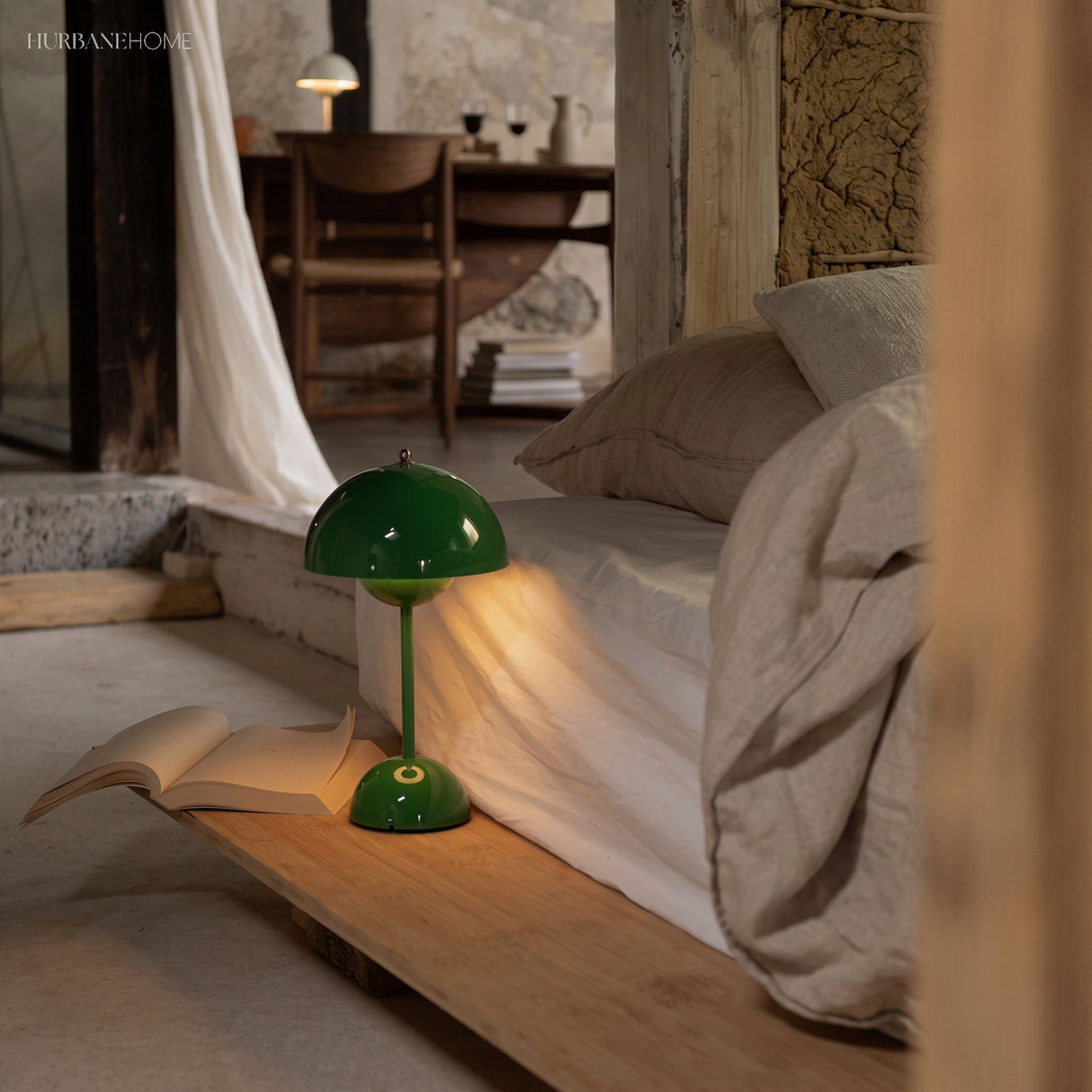 Green rechargeable table lamp lit beside a bed and open book