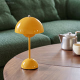 Yellow rechargeable table lamp on a round timber table with a teapot