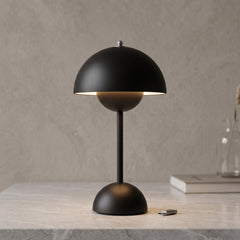 Rechargeable LED table lamp in black with domed shade on a stone surface