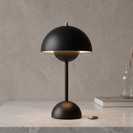 Rechargeable LED table lamp in black with domed shade on a stone surface