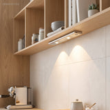 Slim light bar under an oak shelf casting two warm pools on tiles