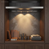 Under cabinet bar lighting a dark stone alcove above books and folded linen