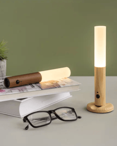 Two cordless wood lamps standing upright on a desk beside reading glasses